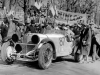 Rudolf Caracciola und Wilhelm Sebastian beim Start zur Mille Miglia 1931 in Brescia. WÃ¤hrend der Starter gerade die letzten Sekunden bis zum Start herunterzÃ¤hlt, verabschiedet sich Caracciolas Frau gerade von ihrem Mann, und Beifahrer Sebastian winkt zum Abschied. Alle Scheinwerfer sind gegen Steinschlag durch Abdeckkappen geschÃ¼tzt, was bei den hÃ¤ufigen NaturstraÃen unbedingt erforderlich ist.